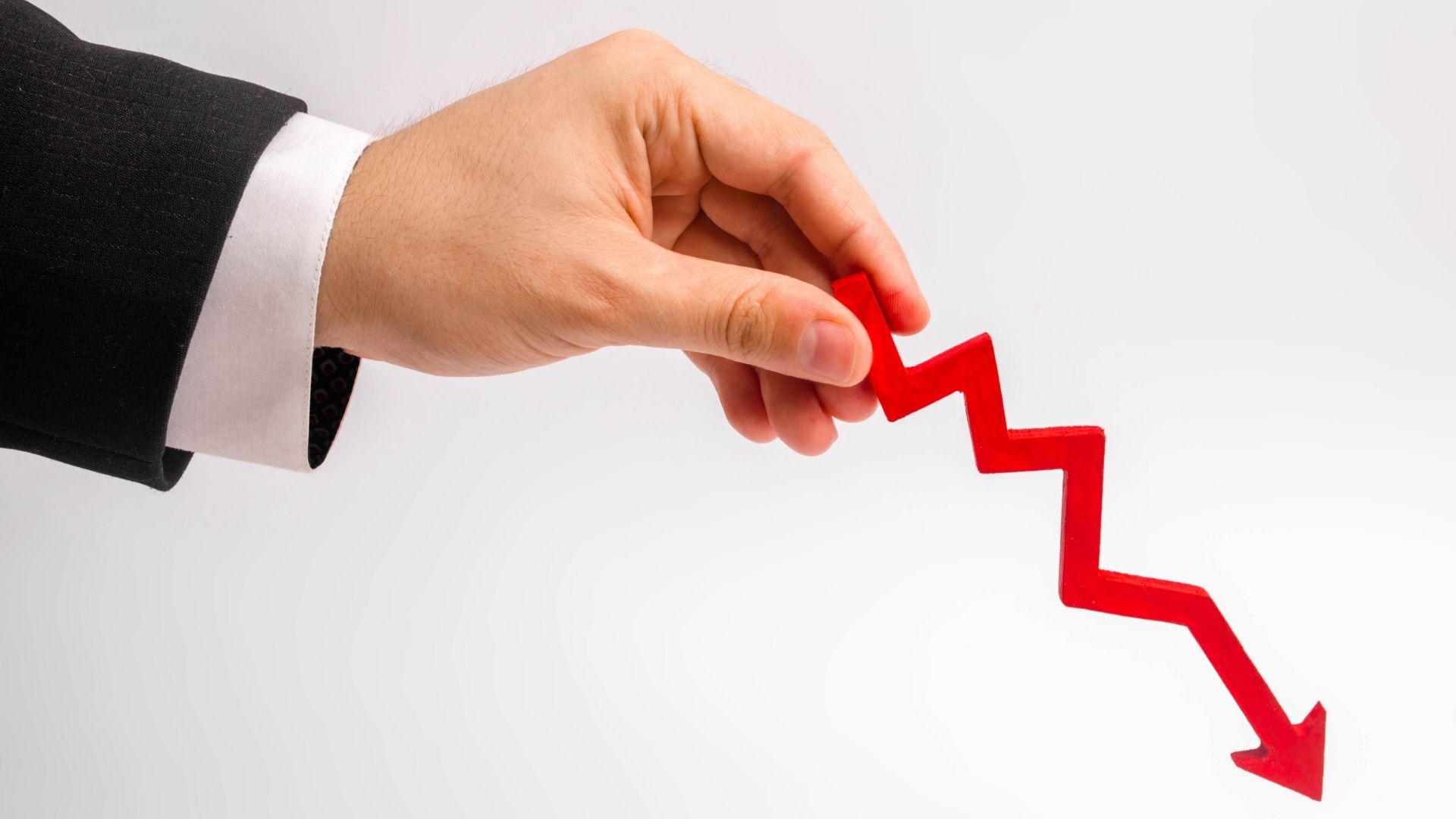 businessman's hand is holding a red arrow down