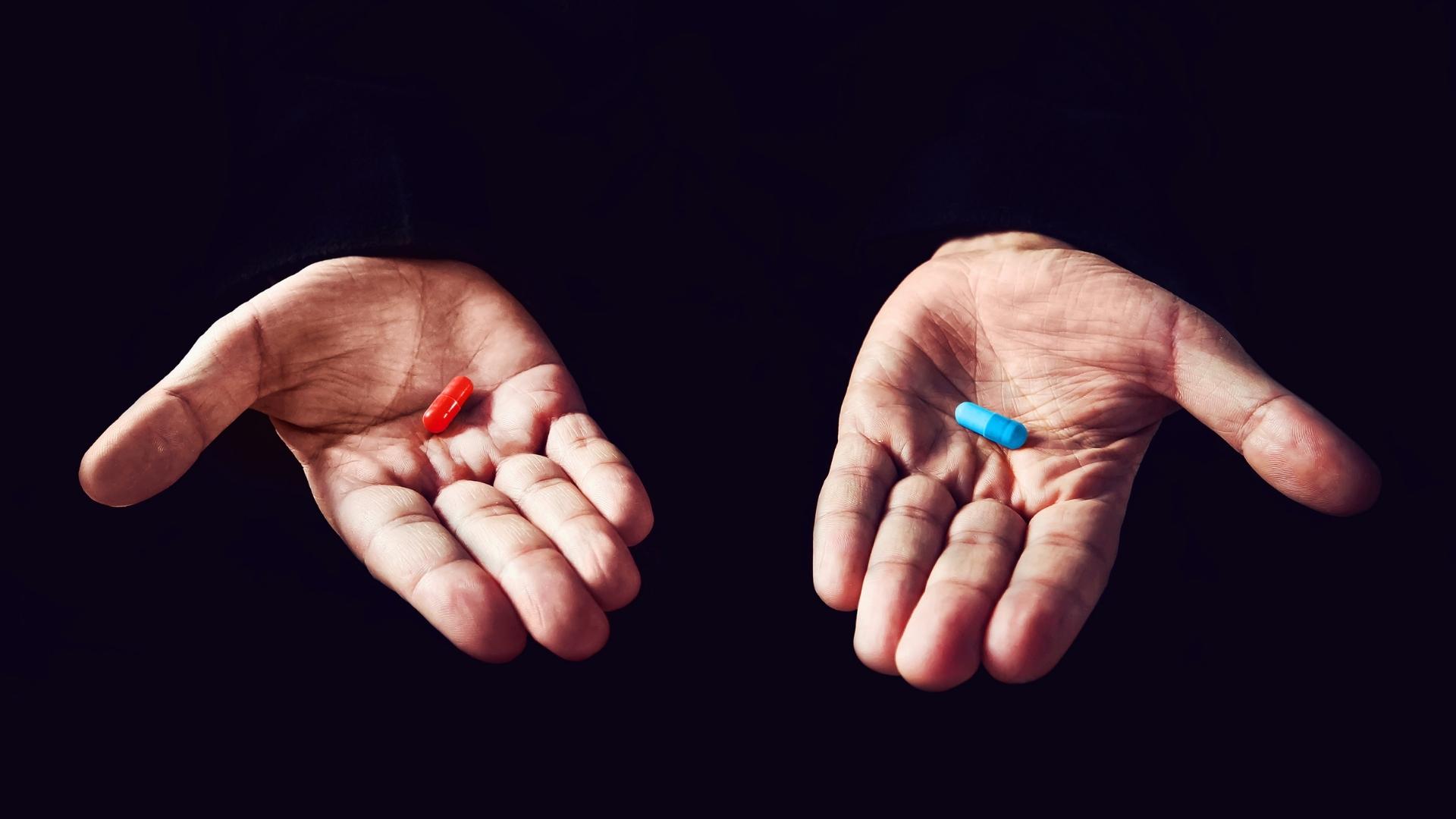 hand holding a blue and red pill