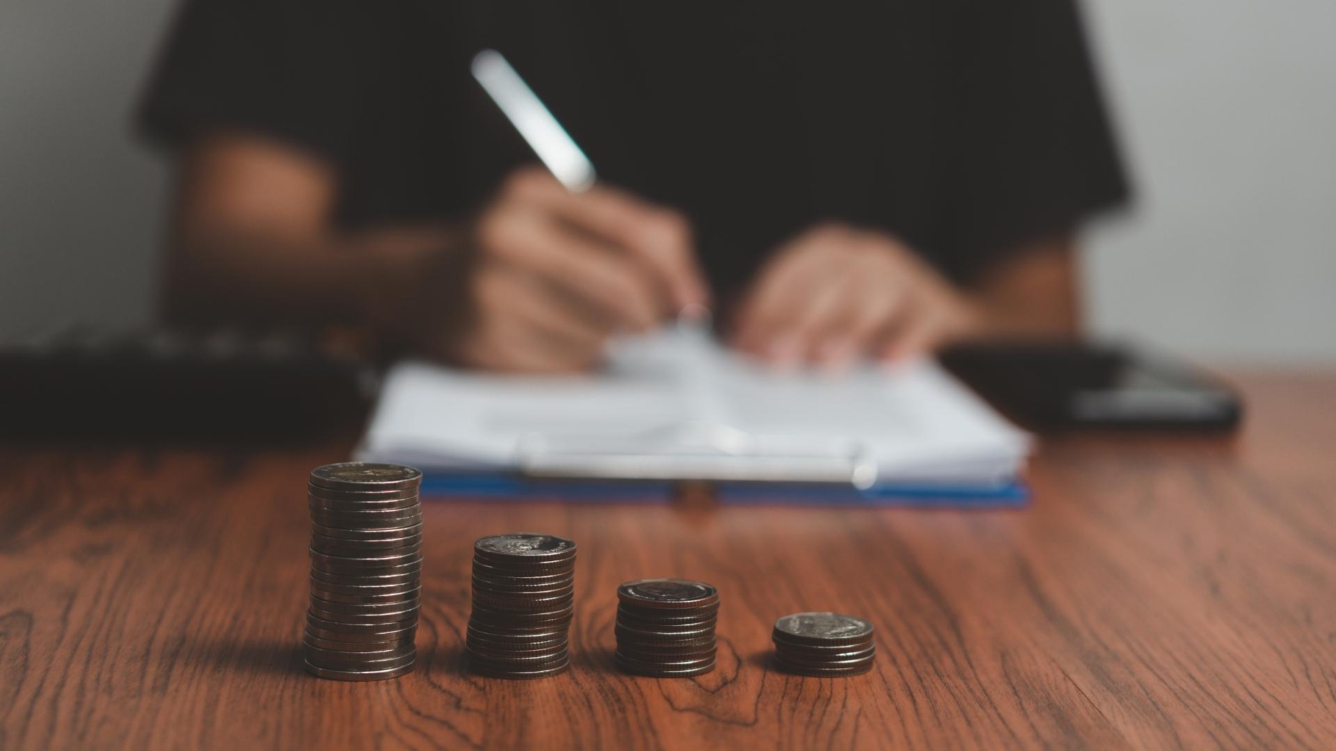 man writing and stack of coins