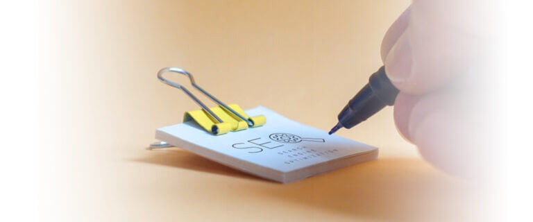 man writing in small piece of paper