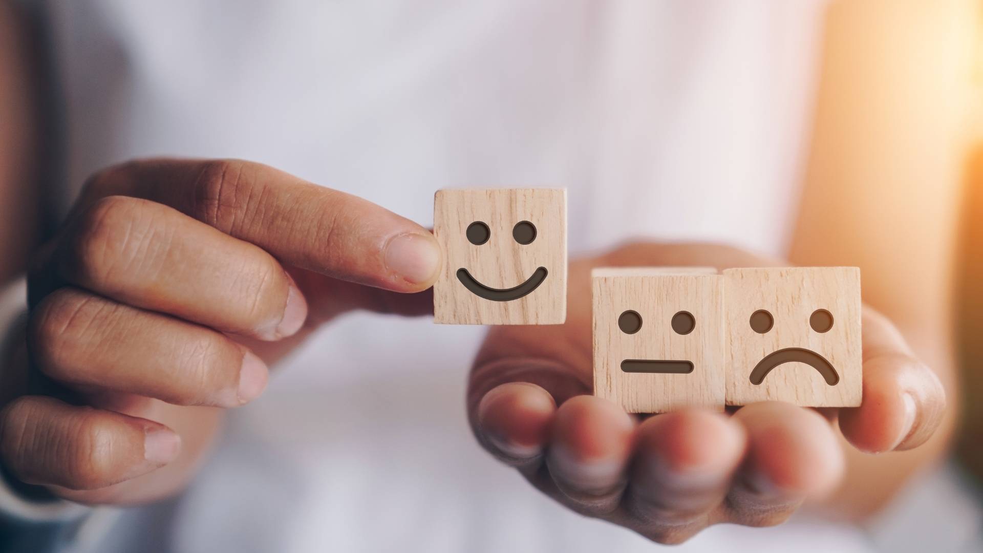 person holding wooden cubes with various emotions