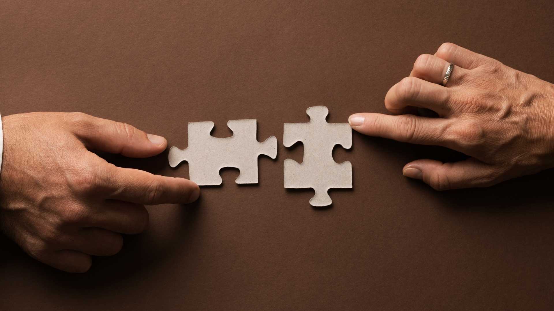 two people joining two matching puzzle pieces