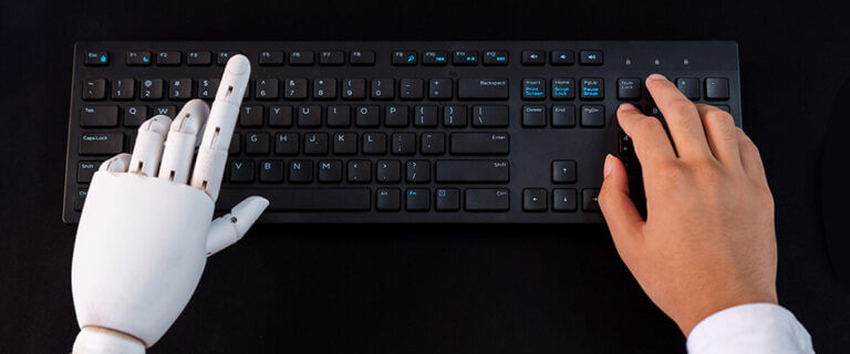 robotic hand and human hand at keyboard