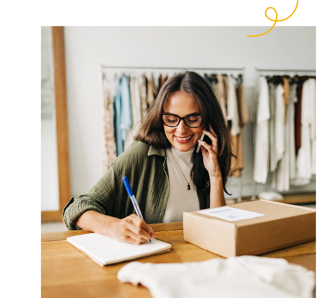 A women talking to someone on her phone while taking a notes