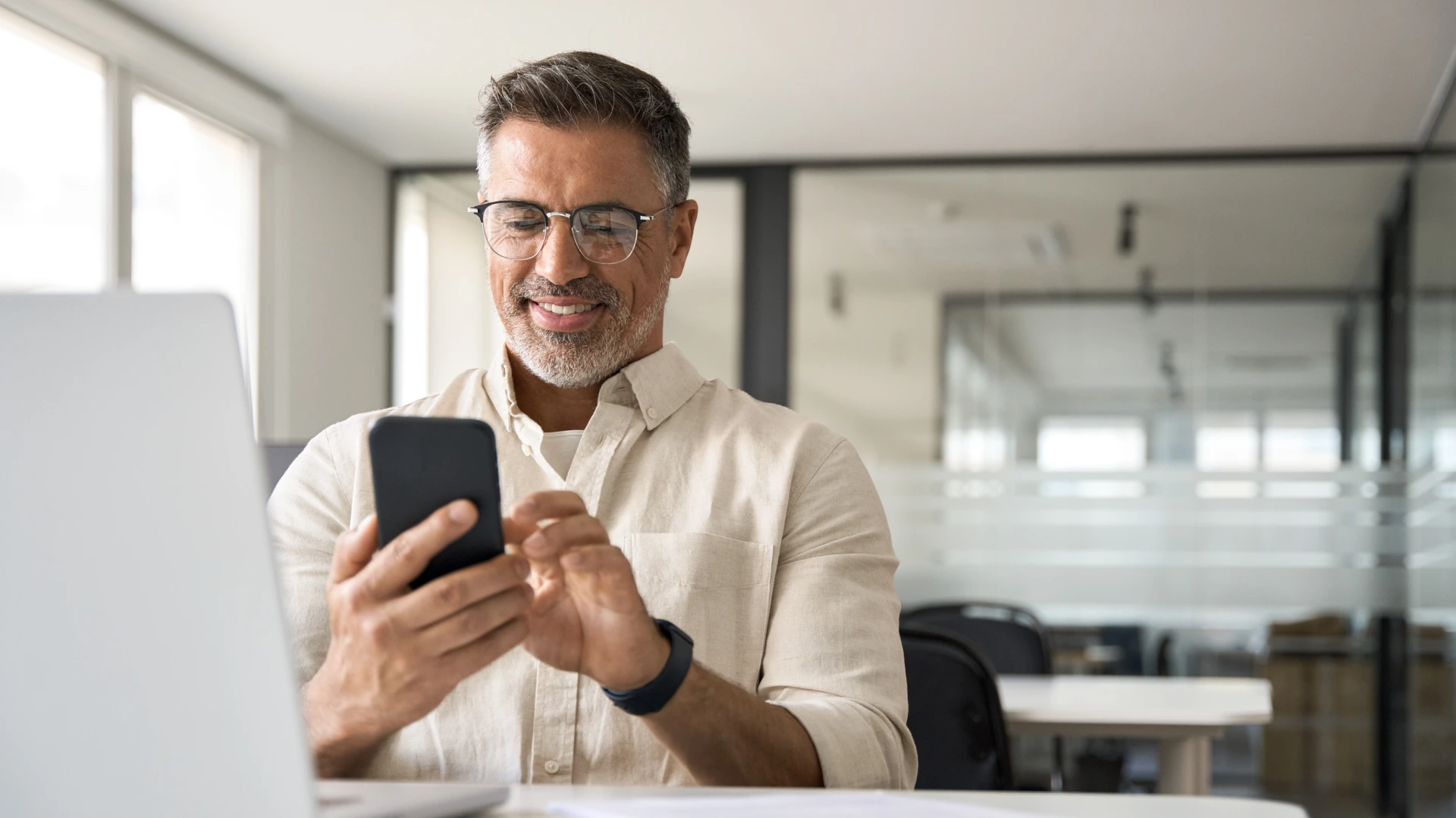 Middle aged Hispanic business manager ceo using cell phone mobile app, laptop.